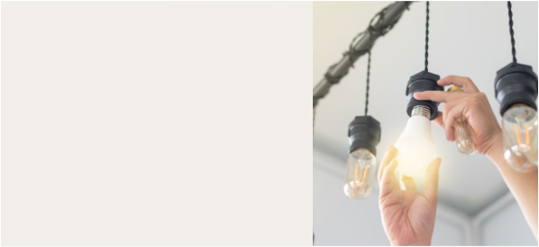 A hand reaching up and unscrewing a lightbulb.